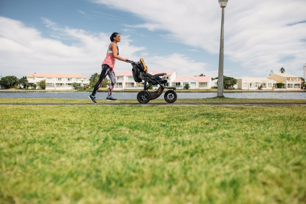 Mother running with a toddler stroller in park