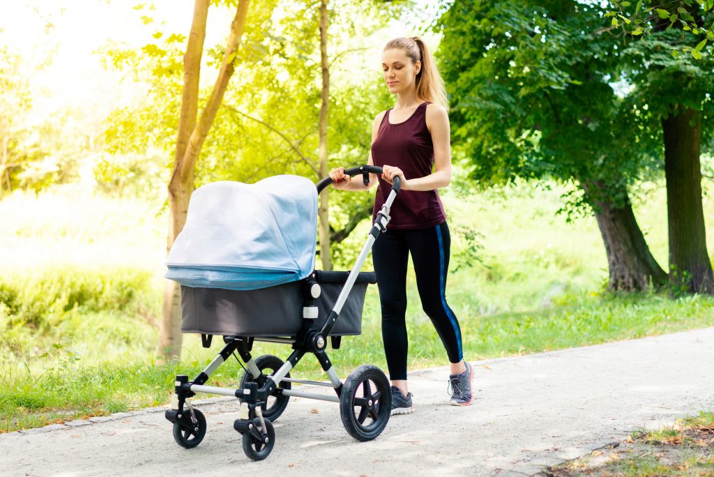 Young active mother doing her exercises with a running Pram